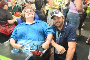 A volunteer in a wheelchair with her carer beside her at a Townsville Community Information Centre community event